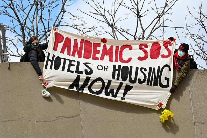 Protesters hold up a banner above Nathan Phillips Square.